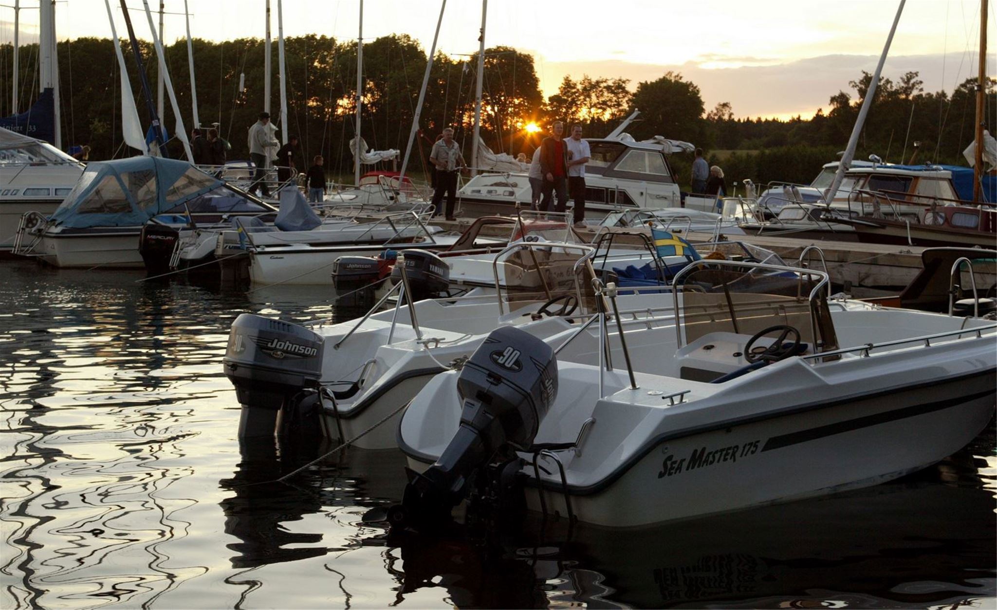 Motorbåtar ligger förtöjda i hamnen under en vacker solnedgång.  Sokord: motorbåt, hamn, båt, solnedgång, skärgård, vatten, kväll · Sok aven: motorboat, harbour, harbor, port, marina, boat, sunset, archipelago, skerries, water, evening