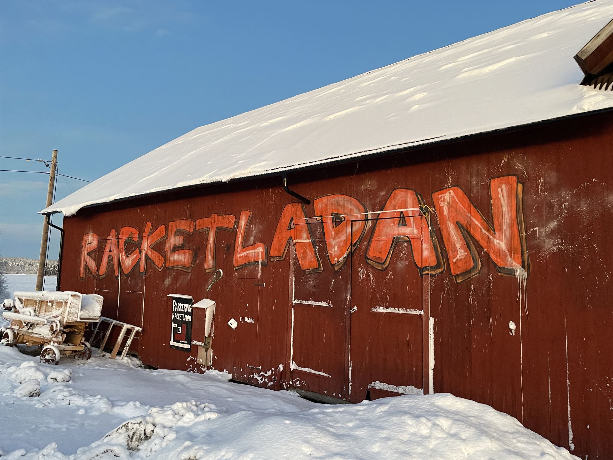 En röd lada med snötäckt tak i en snöig vinterlandskap.  Sokord: lada, röda hus, snö, vinter, skärgård, gård · Sok aven: barn, red cottages, red houses, falu red, snow, winter, archipelago, skerries, farm, courtyard